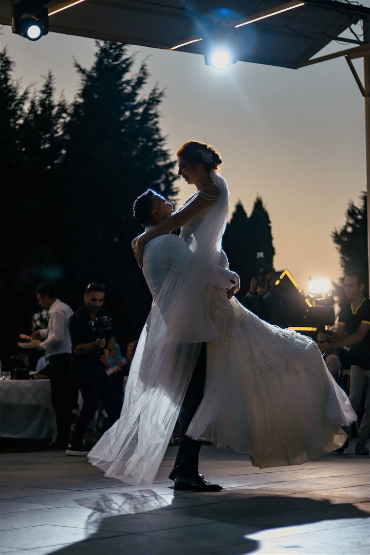 A groom lifts his bride mid-spin on a dance floor at night