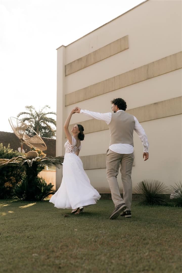A bride twirls with her partner on a lawn