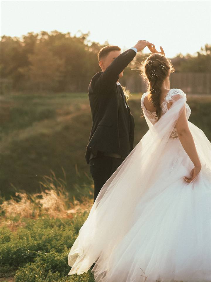 A groom twirls his bride in golden evening light